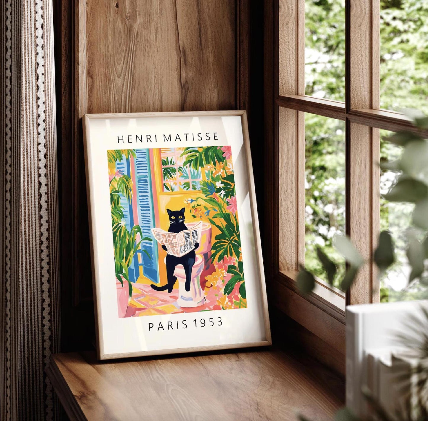 Framed Henri Matisse art print of a black cat reading a newspaper in Paris, displayed in a room with a window and plant.