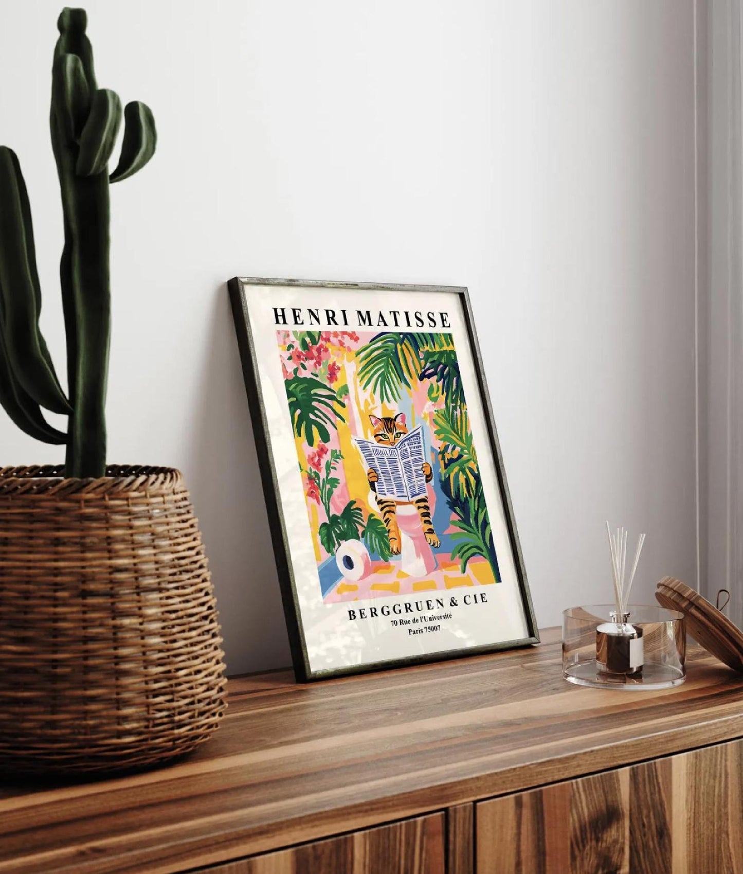 Framed Henri Matisse art print of a tabby cat reading a newspaper in a tropical setting.