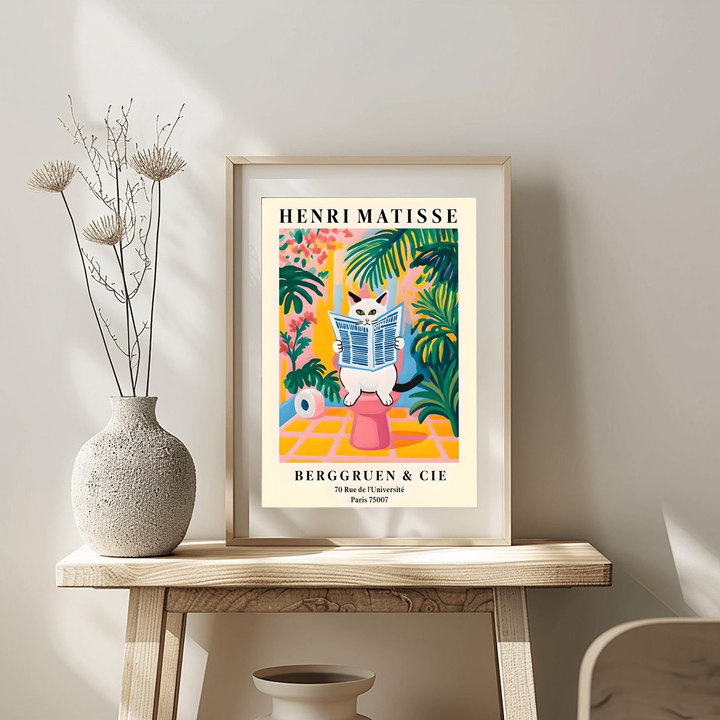 A whimsical, colorful poster in the style of Henri Matisse features an orange and black striped cat with green eyes sitting on a toilet, intently reading a blue-and-white striped newspaper. The bathroom setting is rendered in bold, flat blocks of color, dominated by pink, yellow, and green, with large leafy plants surrounding the cat. A roll of toilet paper is visible to the left. At the top, "HENRI MATISSE" is written in black capital letters.