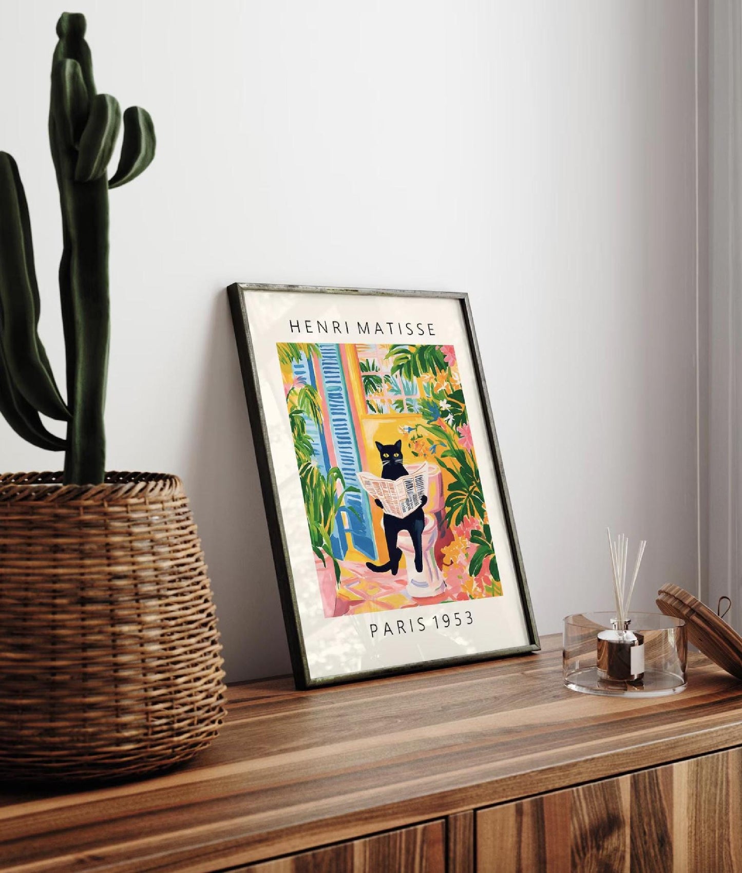 Framed Henri Matisse poster on a wooden surface with a cactus plant.