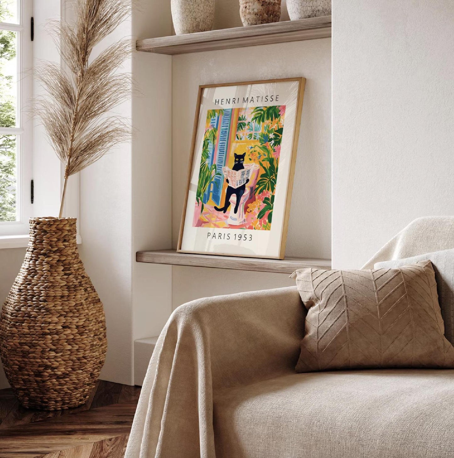 Framed artwork of a cat in a colorful setting on a shelf next to a couch with a pillow.