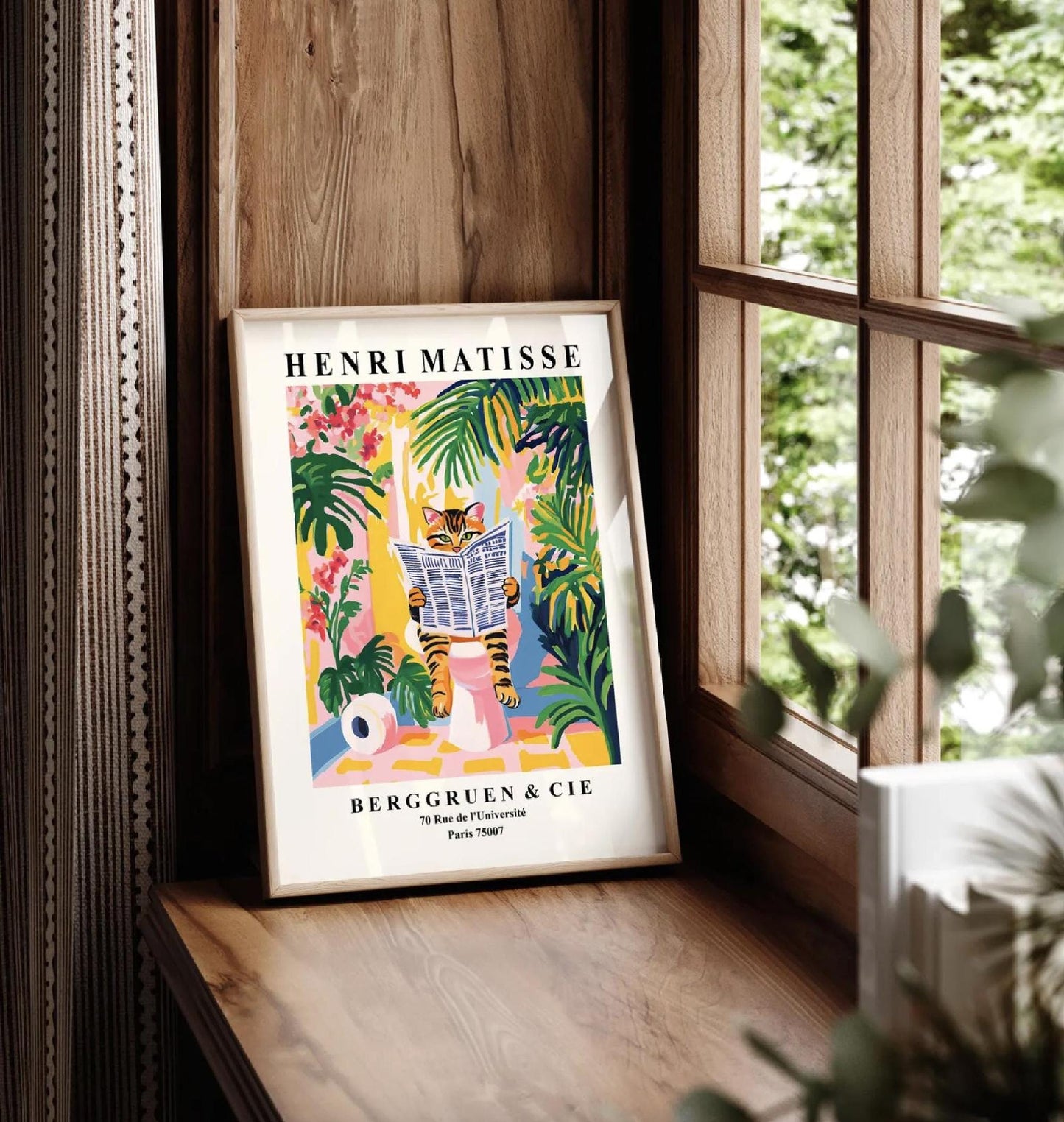 Framed Henri Matisse art print of a tabby cat reading a newspaper in a tropical setting.