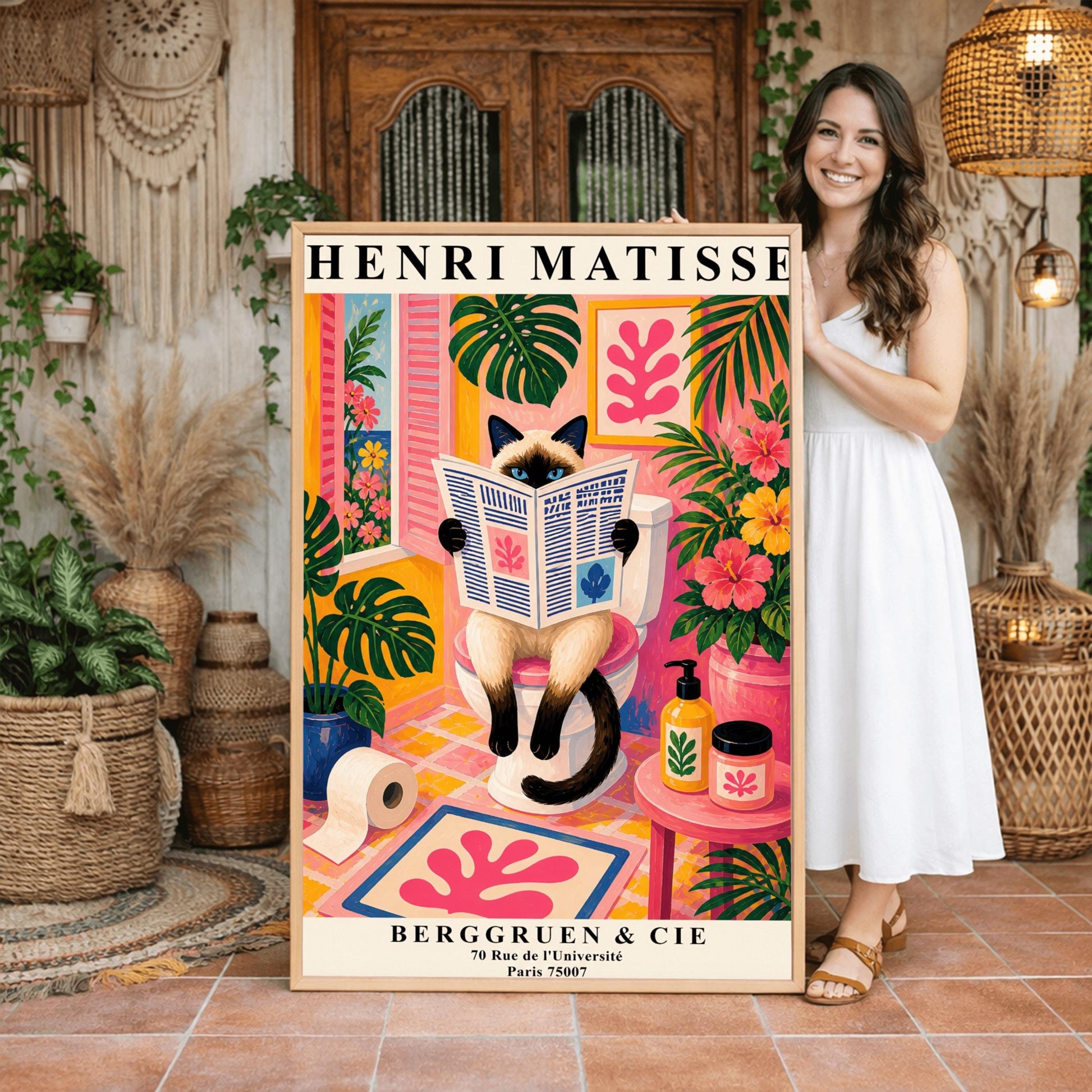 A vertical maximalist art print designed as a Henri Matisse exhibition poster. A cream-colored Siamese cat with dark brown points and blue eyes sits on a toilet, holding and reading a newspaper. The bathroom is vibrantly colored with pink walls, yellow and pink checkered tiles, and lush green monstera plants. A window with pink shutters looks out onto a blue sea. A pink bath mat with a leaf cut-out design and colorful soap jars add to the eclectic decor.