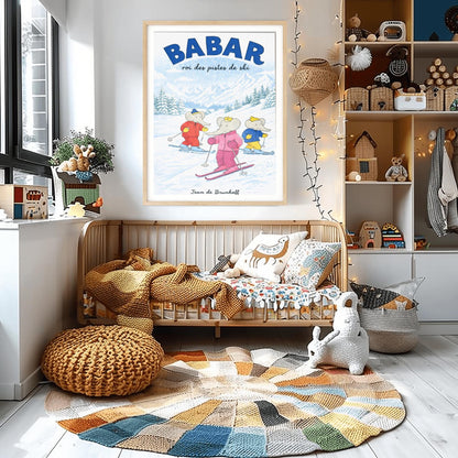 A vertical children's illustration poster titled "BABAR: roi des pistes de ski" in blue. Three elephants are skiing down a gentle, snow-covered slope. The central elephant wears a pink snowsuit and crown. To the left is an elephant in red, and to the right is one in blue and yellow. The background features snowy mountains and a pine forest under a light blue sky. The name "Jean de Brunhoff" is at the bottom.