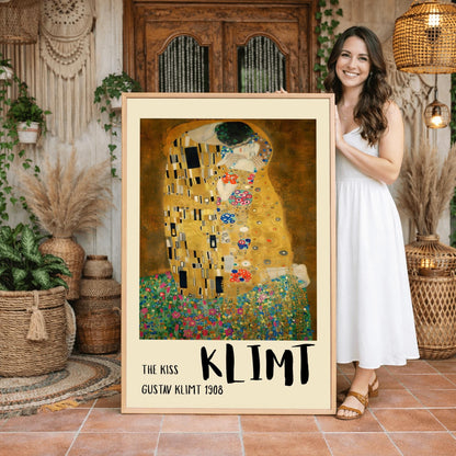 A vertical fine art print of "The Kiss" by Gustav Klimt. Two lovers are shown in an intimate embrace, their bodies covered in elaborate, decorative gold robes. The man's robe features black and white geometric shapes, while the woman's features colorful floral circles. They kneel on a lush bed of colorful wildflowers against a dark, shimmering gold background. The style is rich in mosaic-like patterns and Art Nouveau ornamentation.
