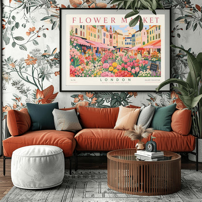 A vintage-style exhibition poster titled "FLOWER MARKET" at the top and "LONDON" at the bottom. The illustration depicts a vibrant open-air market scene packed with dense stalls of pink tulips, yellow ranunculus, and assorted green foliage. In the background, a row of colorful, multi-story pastel buildings stands under a light blue sky with soft white clouds, with shoppers walking between the stalls.