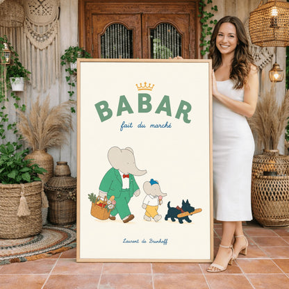 A vertical storybook-style art print of Babar the Elephant walking home from a market against a cream background. Babar is in a green suit and red bow tie, carrying a basket of fruit and flowers. Beside him is a smaller elephant eating an ice cream cone and a small black dog in a plaid collar carrying a baguette. The top text reads "BABAR fait du marché" with a gold crown.