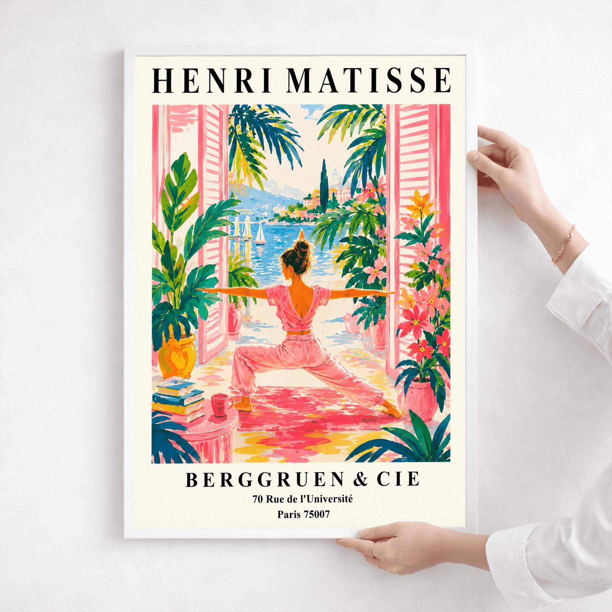 A vertical museum-style exhibition poster with a cream border featuring text for an Henri Matisse exhibition at Berggruen & Cie in Paris,. The colorful central illustration depicts a woman from behind practicing a yoga pose on a pink mat on a terrace. She is framed by open pink shutters and lush green potted plants. Through the open doors is a scenic view of a bright blue sea with sailboats, a coastal hill town, and green palm trees under a sunny sky.