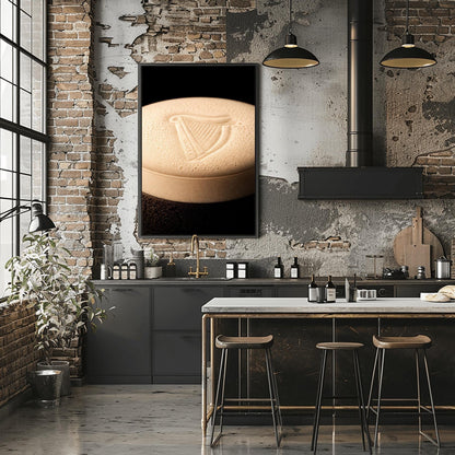 A vertical macro photograph of the thick, creamy foam head on a pint of Guinness. The iconic Guinness harp is embossed into the center of the velvety bubbles. The image features warm cream tones against a dark, shadowy background.