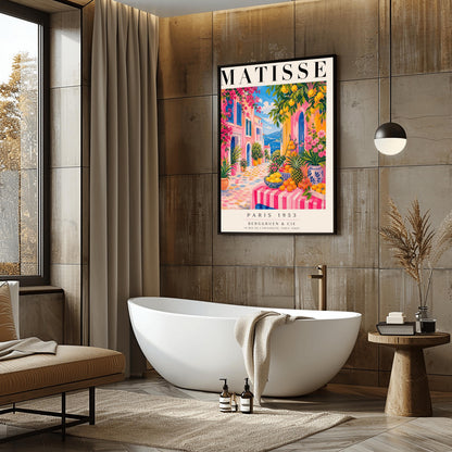 A vertical maximalist art print styled as a Henri Matisse exhibition poster. The scene depicts a vibrant, colorful street in a Mediterranean coastal town. In the foreground, a table with a pink and white striped cloth is piled high with lemons, oranges, and a pineapple. Hot pink and yellow buildings with blue shutters line a cobblestone path that leads toward a blue sea under a bright sky. Lush green trees with yellow lemons and pink flowers frame the view.