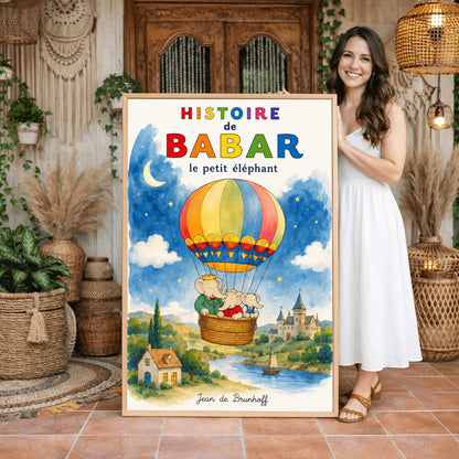 A vertical retro fine art exhibition poster titled "HISTOIRE de BABAR le petit éléphant" with a wide cream border. The illustration features a colorful hot air balloon carrying three elephants—one with a crown—floating in a sky that is half daytime blue and half starry dark blue with a crescent moon. Below them is a watercolor landscape of a river with a sailboat, a cottage, and a turleted castle. The signature "Jean de Brunhoff" anchors the bottom.