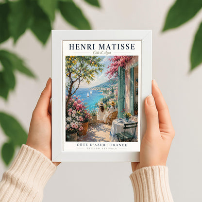 A vertical retro French exhibition poster for Henri Matisse Côte d'Azur on a wide ivory border, as seen in Screenshot 2026-06-06 at 23.18.59.png. The main image shows a beautiful summer illustration of a stone terrace overlooking the blue Mediterranean Sea where two white sailboats float. On the terrace, two women wearing white dresses and straw hats sit facing the water. To the left stands a green lemon tree with yellow fruit and large pots of pink and white flowers.