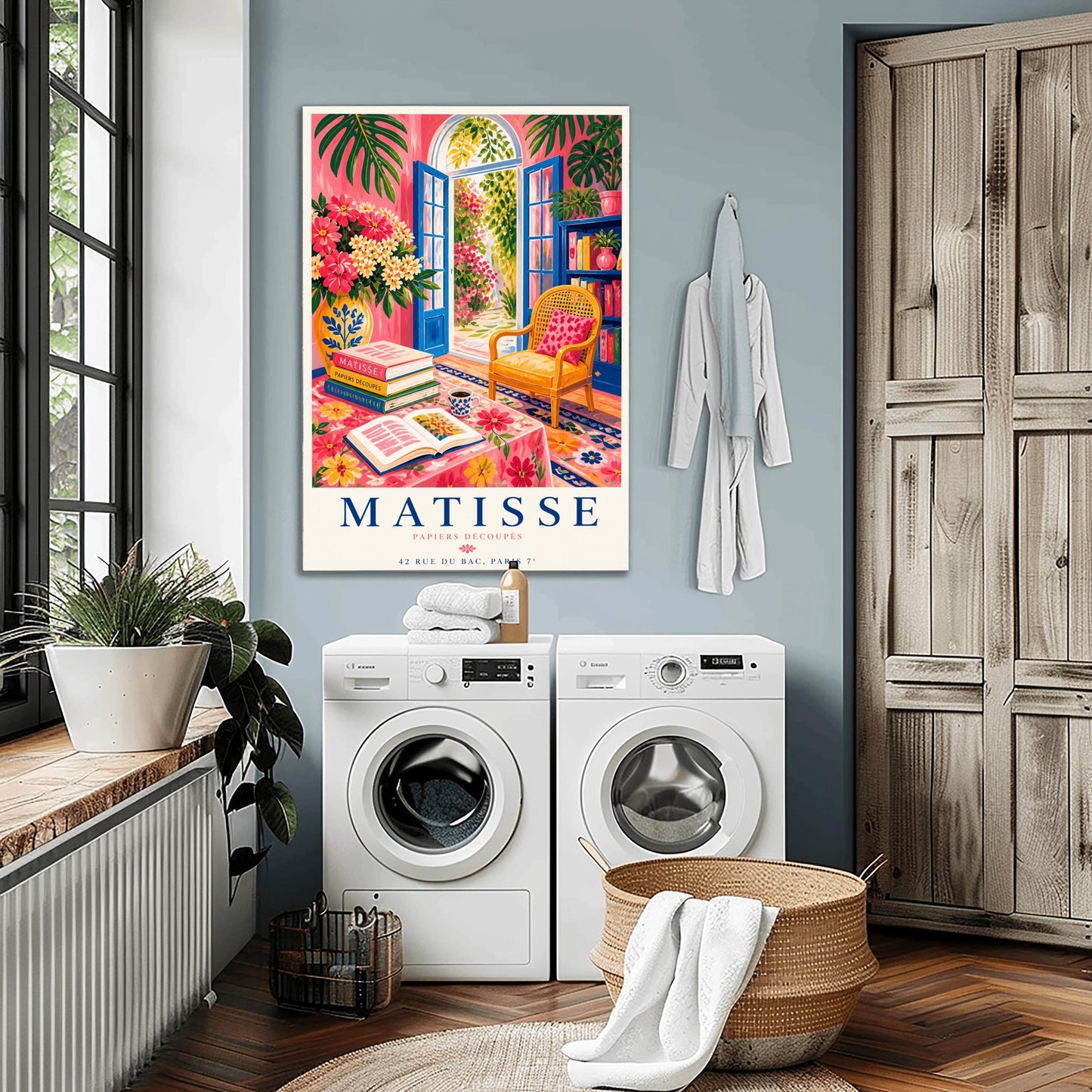 A vertical maximalist art print styled as a Henri Matisse exhibition poster. The scene shows a vibrant interior reading room with hot pink walls and cobalt blue French doors open to a sunlit garden. A yellow cane chair sits next to a bookshelf. In the foreground, a table covered in a pink floral cloth holds a stack of art books, an open book, and a blue coffee mug. Large monstera leaves and various flowers frame the room. Bold black and red text at the bottom reads "MATISSE PAPIERS DÉCOUPÉS"