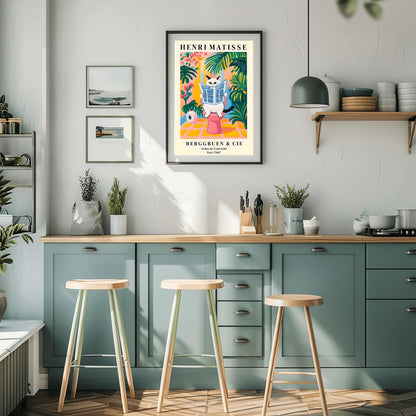 A whimsical, colorful poster in the style of Henri Matisse features an orange and black striped cat with green eyes sitting on a toilet, intently reading a blue-and-white striped newspaper. The bathroom setting is rendered in bold, flat blocks of color, dominated by pink, yellow, and green, with large leafy plants surrounding the cat. A roll of toilet paper is visible to the left. At the top, "HENRI MATISSE" is written in black capital letters.