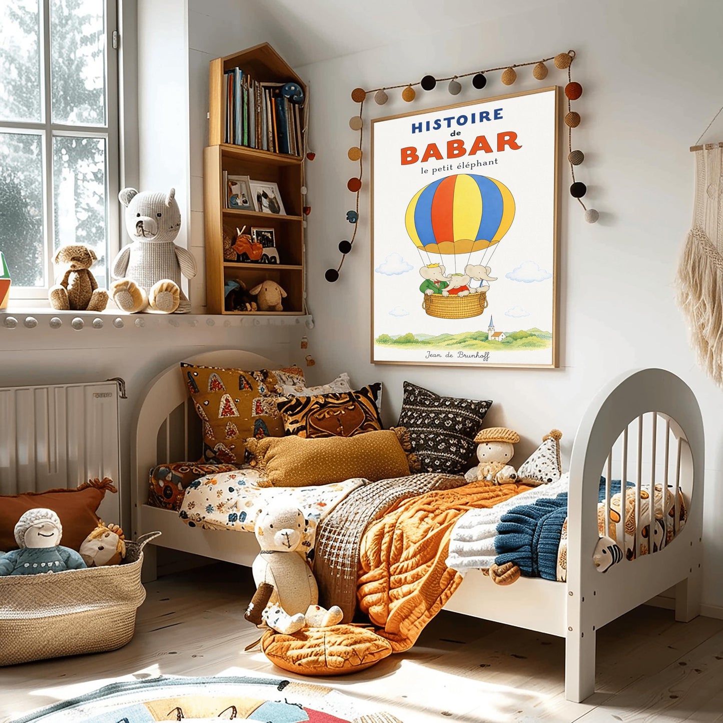 A vertical vintage-style storybook poster on an off-white background titled "HISTOIRE de BABAR le petit éléphant" in bold blue and orange font. The illustration features a large hot air balloon with yellow, blue, and orange stripes floating in a sky with soft clouds. Inside the wicker basket, three cartoon elephants ride together. On the left, King Babar wears a green suit and crown while pointing ahead. The other two young elephants wear red and white shirts.