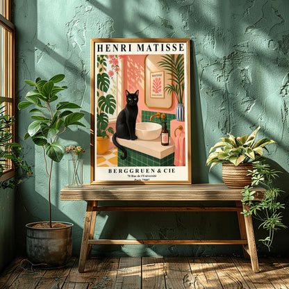 A vertical art print styled as a Henri Matisse exhibition poster. A sleek black cat with bright green eyes sits on a cream-colored bathroom vanity next to a white vessel sink. The bathroom features blush pink walls and emerald green tiles. A gold-framed mirror reflects a Matisse leaf print. Lush green plants and pink flowers frame the scene, and dappled sunlight creates shadows on the wall. The poster has bold black text at the top and bottom with the gallery name Berggruen & Cie.