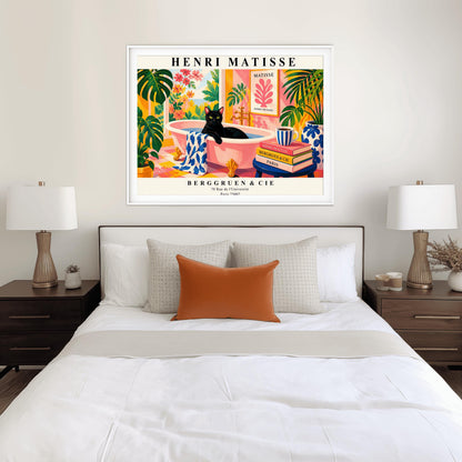 A horizontal art print designed as a Henri Matisse exhibition poster. A sleek black cat sits inside a pink clawfoot bathtub filled with water. The bathroom is vibrant with pink patterned walls, pink and yellow checkered tiles, and numerous large green Monstera plants. Outside the window is a bright garden with pink and orange flowers. A stack of art books and a striped mug sit on a blue stool in the foreground. The poster features bold black text at the top and bottom for "Henri Matisse"