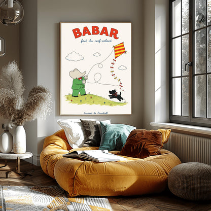 A vertical retro fine art exhibition poster titled "BABAR fait du cerf-volant" on a wide cream border. The top "BABAR" text is printed in a bold red font. The illustration shows an elephant in a green suit and red bowtie flying a red and yellow striped diamond kite on a green grassy hill with small flowers. A small black dog in a plaid scarf runs on the hill below, and the name "Laurent de Brunhoff" anchors the bottom.