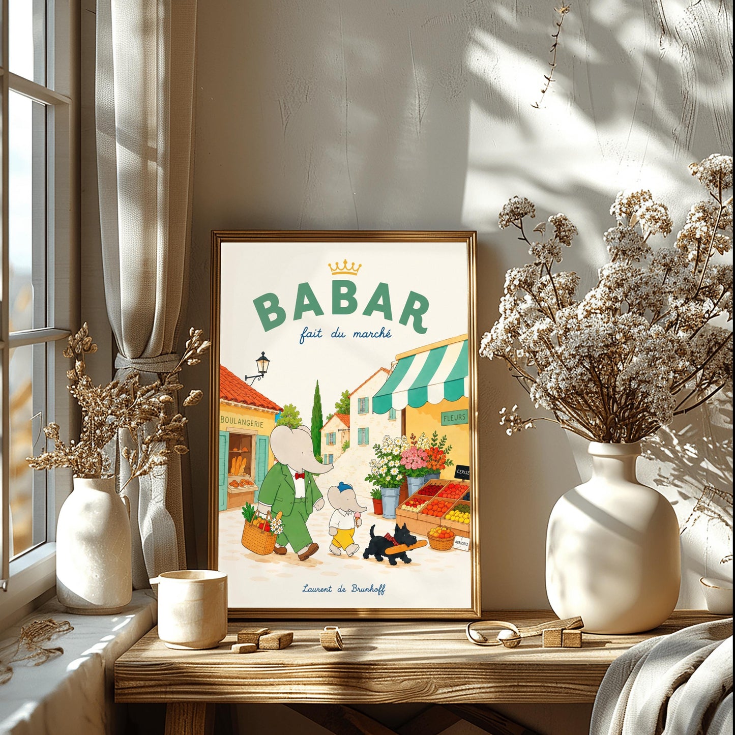 A vertical storybook-style art print of Babar the Elephant walking through a French village street. Babar, in a green suit, carries a basket of groceries. A smaller elephant walks beside him eating a pink ice cream cone, followed by a black dog carrying a baguette. The background features a boulangerie with a yellow facade, a flower stall with pink and white roses, and terracotta-roofed houses under a cream sky. The top reads "BABAR fait du marché" with a gold crown.