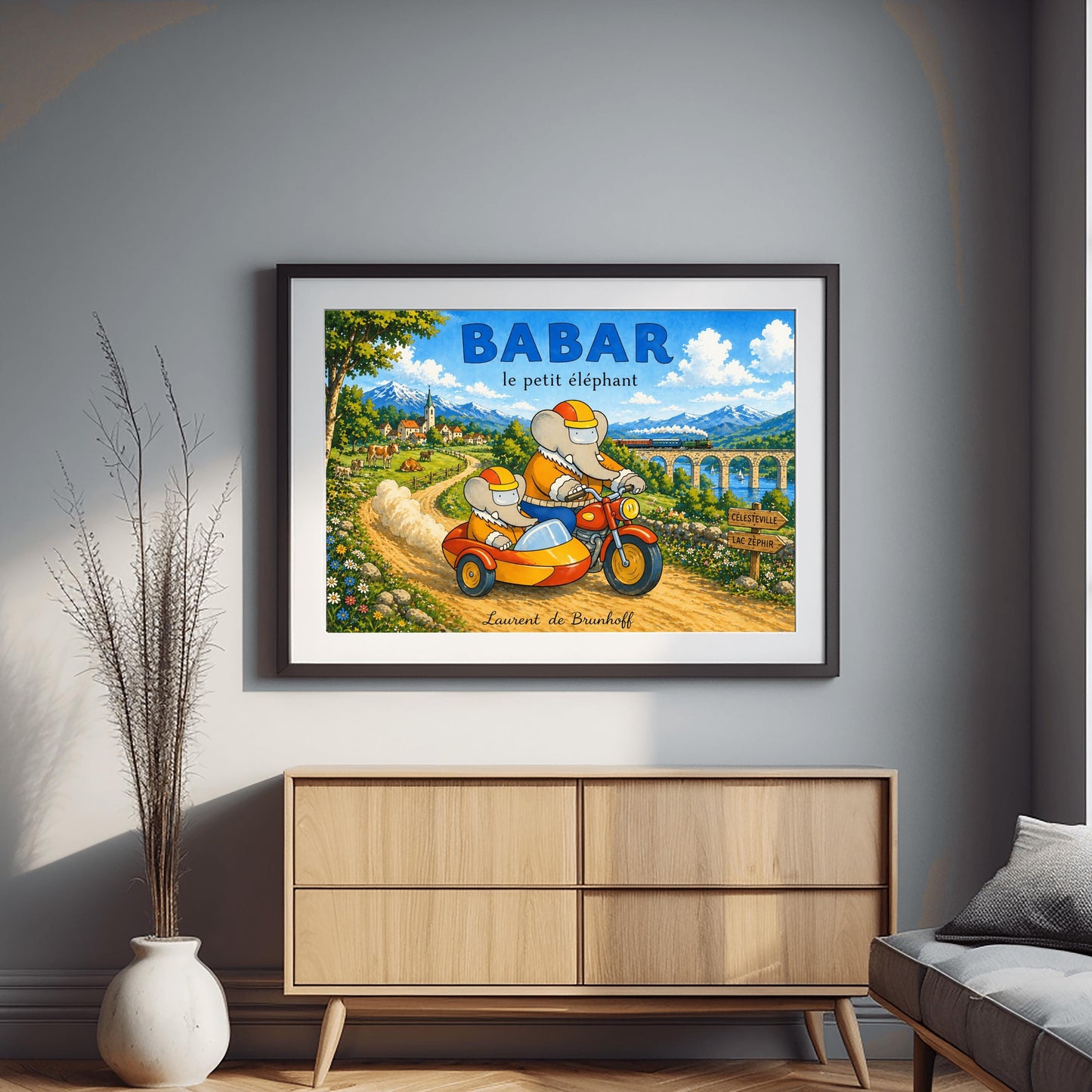 A horizontal watercolor illustration featuring Babar the Elephant and a smaller elephant riding a red motorcycle with a yellow sidecar down a dirt road. Both wear orange jackets and orange-and-yellow helmets. They are driving away from a European village toward a valley where a train crosses a stone bridge. In the background are tall, snow-capped mountains under a blue sky. A wooden sign points toward "Célesteville" and "Lac Zéphir."