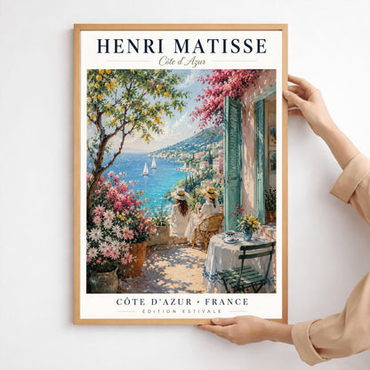A vertical retro French exhibition poster for Henri Matisse Côte d'Azur on a wide ivory border, as seen in Screenshot 2026-06-06 at 23.18.59.png. The main image shows a beautiful summer illustration of a stone terrace overlooking the blue Mediterranean Sea where two white sailboats float. On the terrace, two women wearing white dresses and straw hats sit facing the water. To the left stands a green lemon tree with yellow fruit and large pots of pink and white flowers.