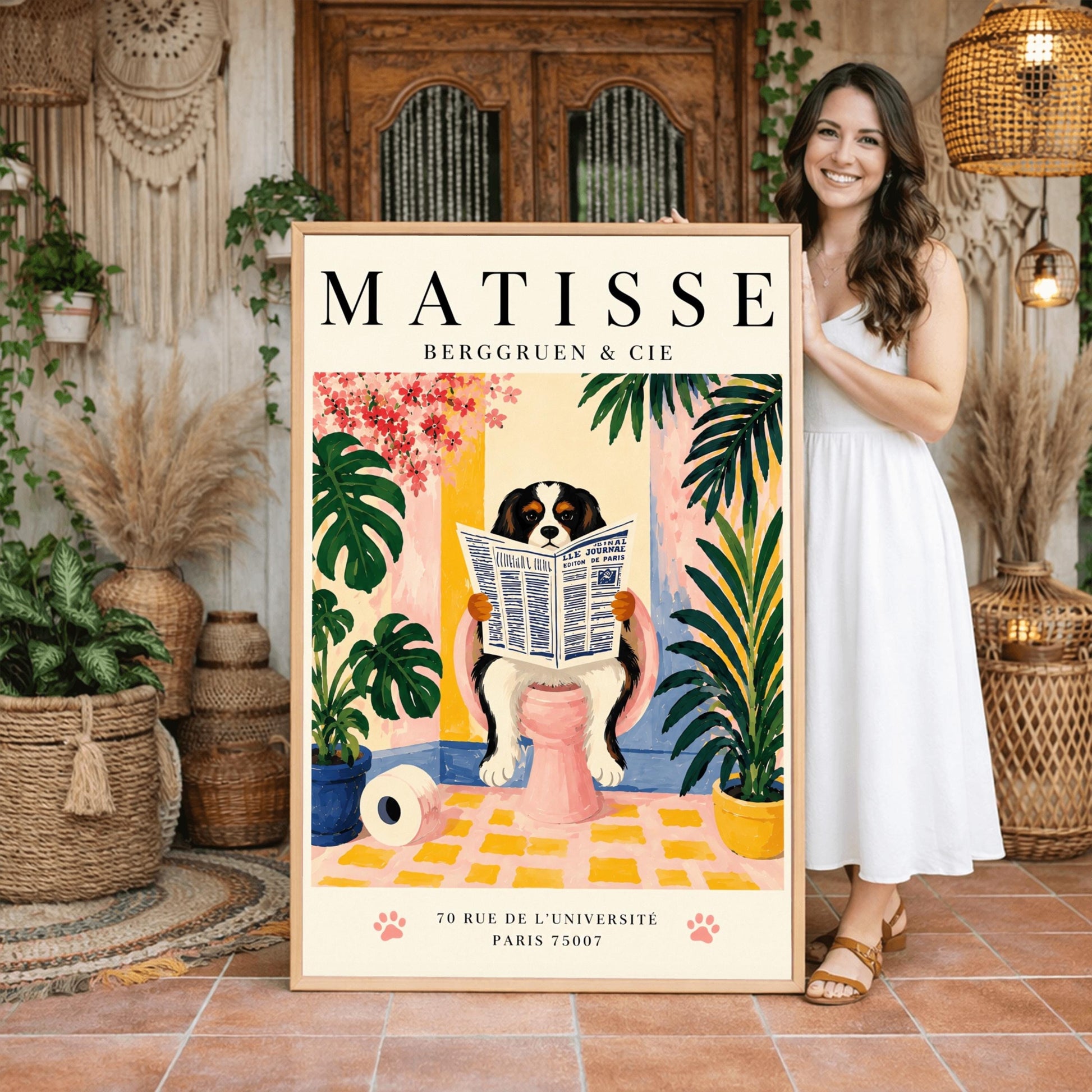 A vertical vintage-style exhibition poster on a cream background titled "MATISSE BERGGRUEN & CIE" in bold black font. The main gouache-style illustration depicts a tricolor black, white, and tan Cavalier King Charles Spaniel sitting on a pink toilet. The dog is holding and reading a blue-and-white French newspaper titled "LE JOURNAL". The bathroom scene includes a roll of toilet paper on a yellow checkered floor, potted monstera and palm plants