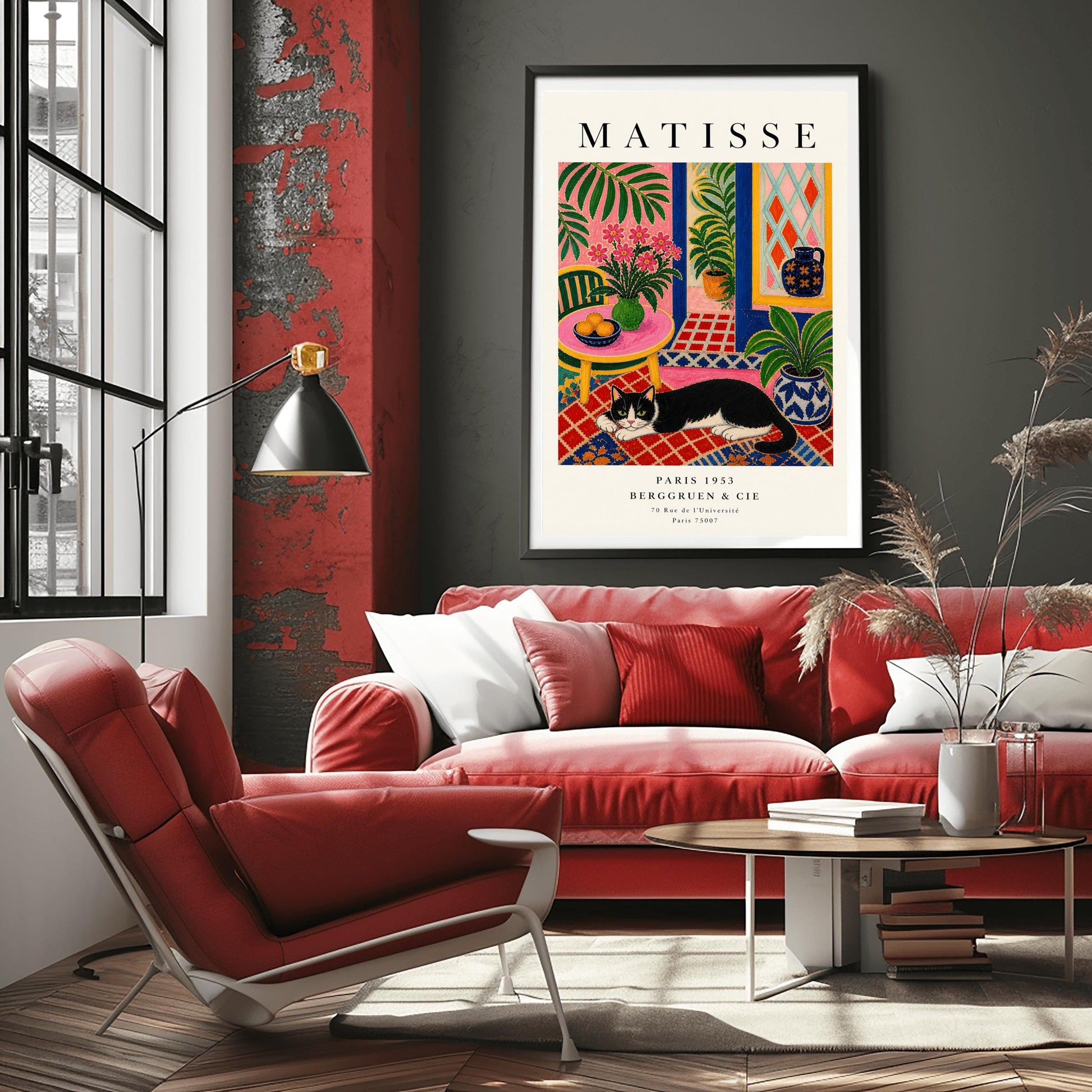 A vertical maximalist art print styled as a Henri Matisse exhibition poster. A black and white tuxedo cat lies across an intricate red, orange, and blue patterned rug. The room features textured bubblegum pink walls and a cobalt blue door frame. To the left, a pink table holds a bowl of oranges and a green vase with pink flowers. To the right, a blue and white floral pot holds a green plant. A diamond-patterned window is visible in the background.