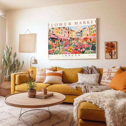 A vintage-style exhibition poster titled "FLOWER MARKET" at the top and "LONDON" at the bottom. The illustration depicts a vibrant open-air market scene packed with dense stalls of pink tulips, yellow ranunculus, and assorted green foliage. In the background, a row of colorful, multi-story pastel buildings stands under a light blue sky with soft white clouds, with shoppers walking between the stalls.