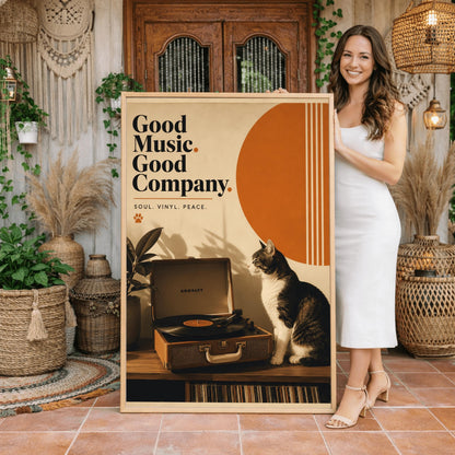A vertical retro fine art poster titled "Good Music. Good Company." on a wide cream border. The design features a bold black serif heading on the left above the text "SOUL. VINYL. PEACE." and a small orange paw print. In the central artwork, a black and white tuxedo cat sits contentedly next to an open tan Crosley record player spinning a vinyl record. A large orange sun shape with white vertical stripes and a potted rubber plant decorate the background.
