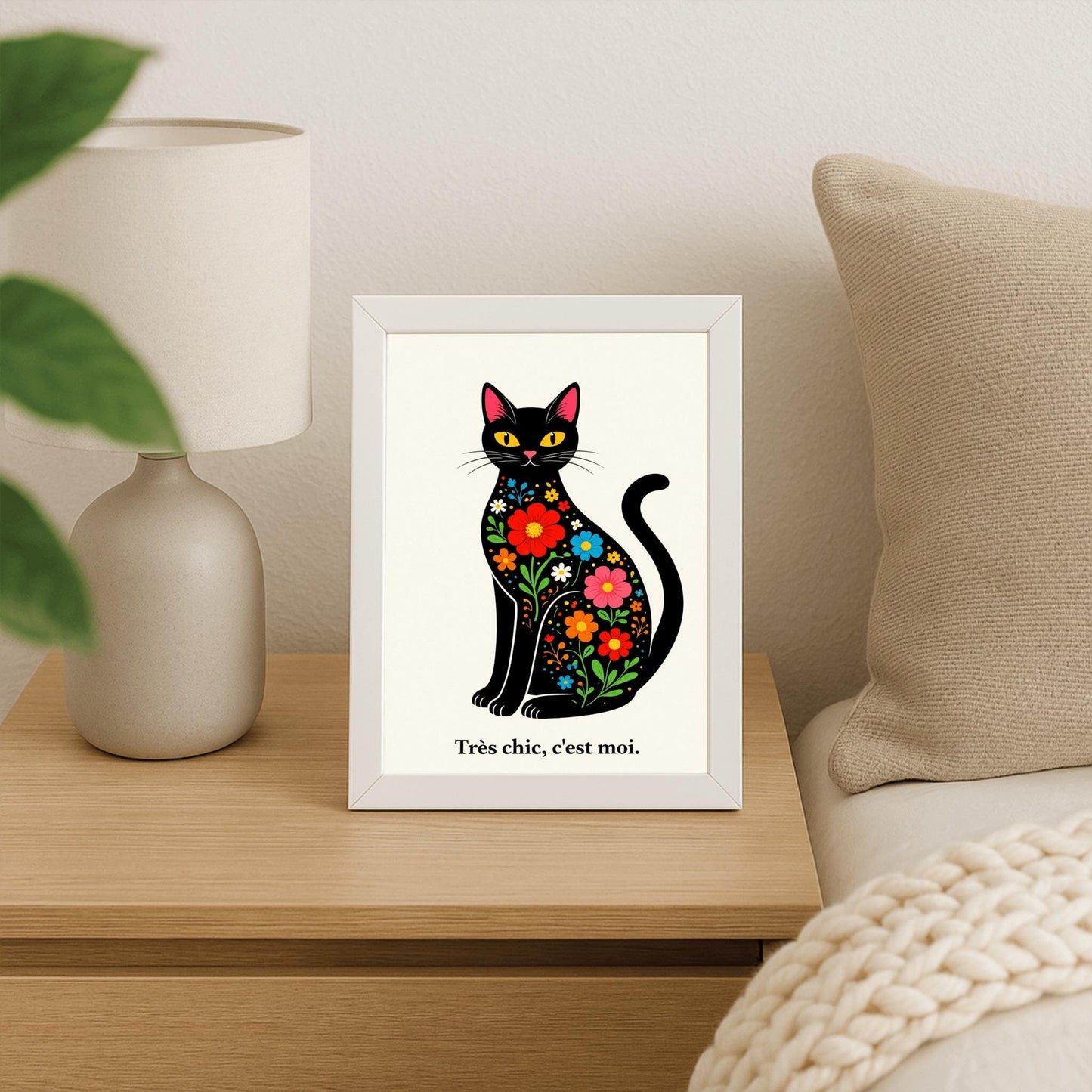 A vertical minimalist art print of a sleek black cat sitting upright, facing forward. The cat's body is filled with colorful folk-art style flowers in red, blue, orange, and yellow with green leaves. The cat has large yellow eyes and a small pink nose. Below the cat, the French phrase "Très chic, c'est moi." is written in a black serif font. The entire image is set against a textured off-white background.