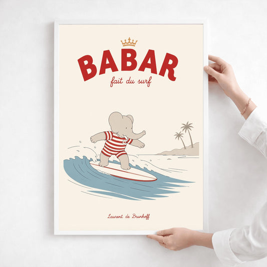 A vertical storybook-style art print of Babar the Elephant surfing. Babar is wearing a red and white striped swimsuit and standing on a white surfboard with a red stripe. He is riding a blue wave with a white crest. In the background, there is a tan beach with two palm trees under a cream sky. The top reads "BABAR fait du surf" with a small gold crown.