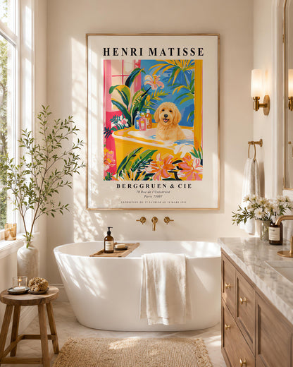 A vertical minimalist fine art exhibition poster in the style of Henri Matisse, shown framed on a wall above a luxury white bathtub. The poster has a wide white border with bold black text reading "HENRI MATISSE" and "BERGGRUEN & CIE". In the center painting, a fluffy golden doodle dog sits happily inside a yellow bathtub surrounded by vibrant pink, blue, and green tropical plants and orange flowers.