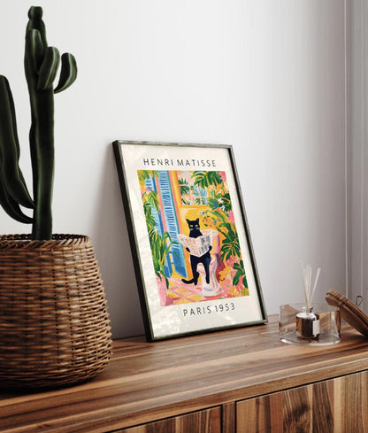 Framed Henri Matisse poster on a wooden surface with a cactus plant.