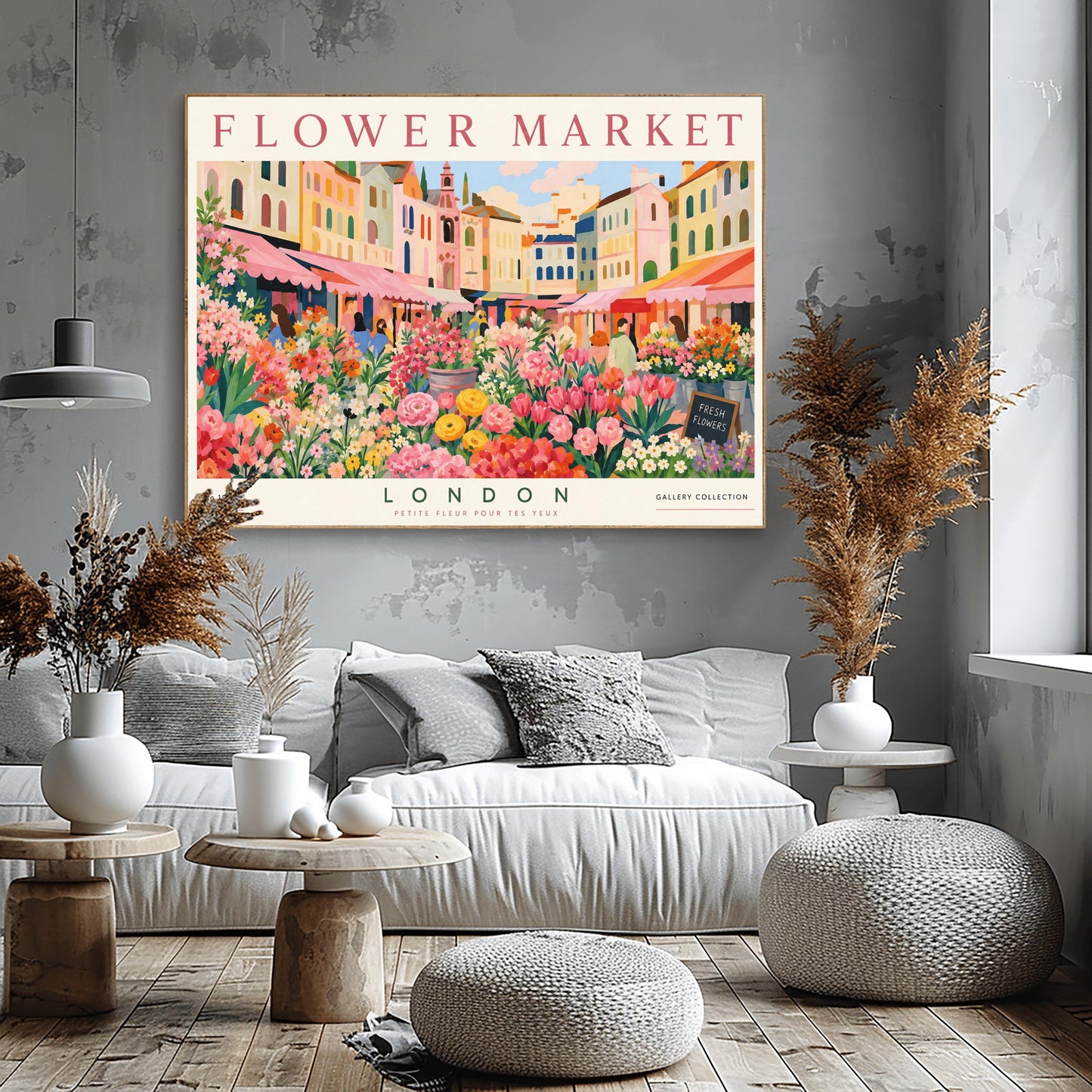 A vintage-style exhibition poster titled "FLOWER MARKET" at the top and "LONDON" at the bottom. The illustration depicts a vibrant open-air market scene packed with dense stalls of pink tulips, yellow ranunculus, and assorted green foliage. In the background, a row of colorful, multi-story pastel buildings stands under a light blue sky with soft white clouds, with shoppers walking between the stalls.