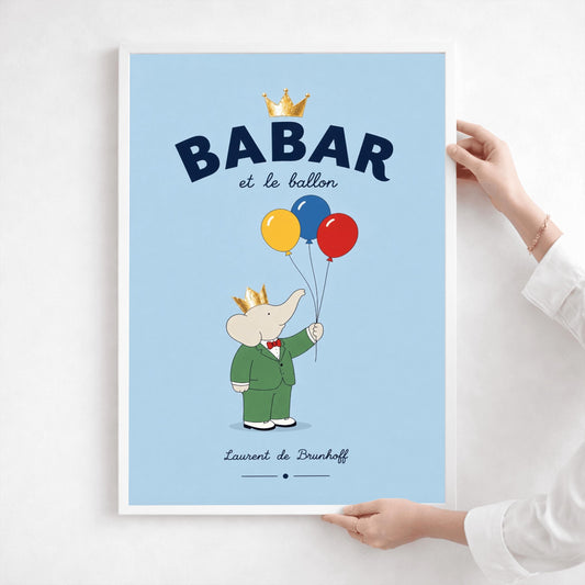 A vertical minimalist children's art print of Babar the Elephant standing on a light blue background. Babar is wearing a green suit, red bowtie, and a golden crown. He is holding the strings to three large balloons in red, yellow, and blue. At the top, bold dark blue text reads "BABAR" with a gold crown above it and "et le ballon" in script below. The name "Laurent de Brunhoff" is centered at the bottom.