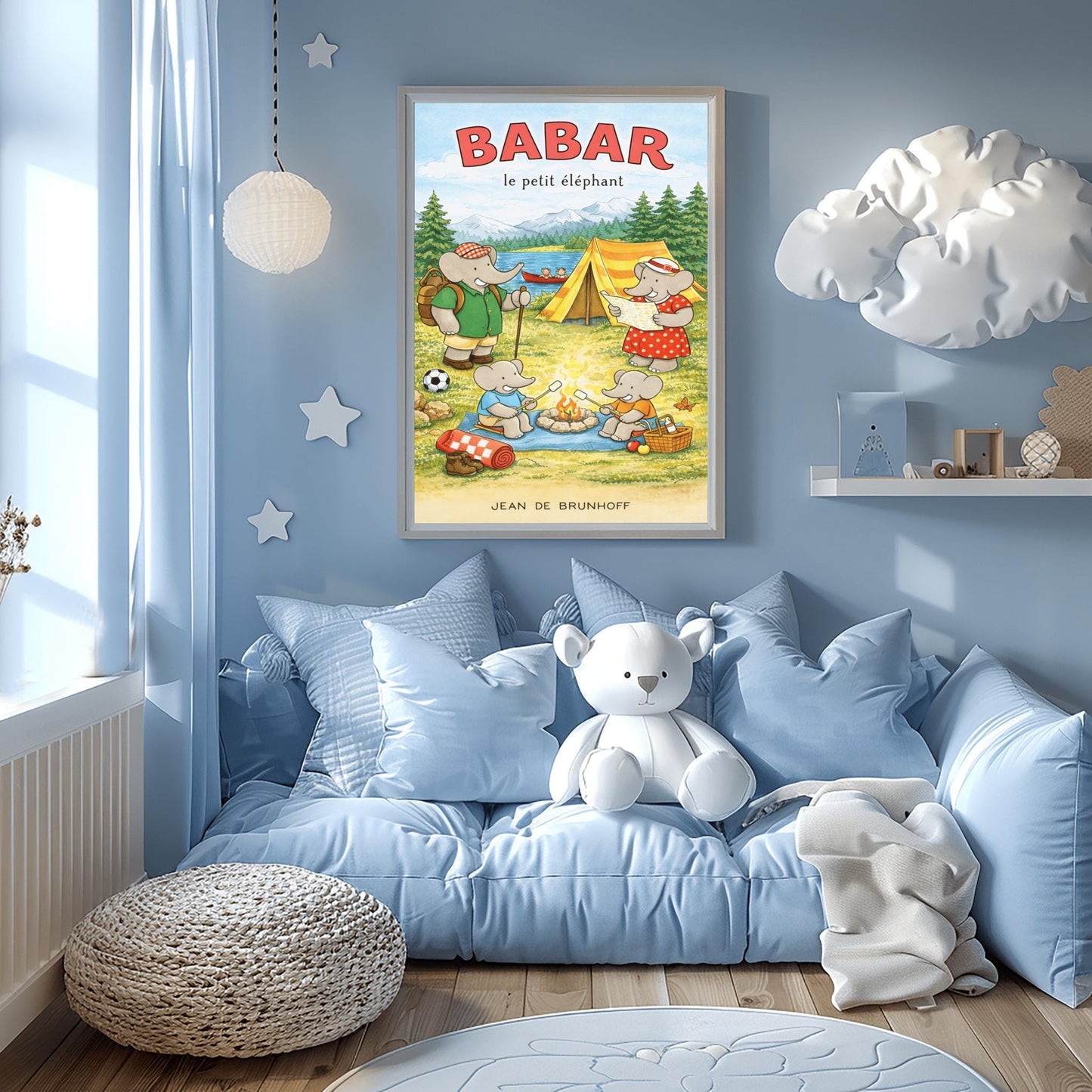 A vertical children's illustration poster titled "BABAR le petit éléphant" at the top in red. It features an elephant family camping by a lake. A large elephant (Babar) in a green shirt stands to the left with a backpack and walking stick. Another large elephant (Celeste) in a red polka-dot dress looks at a map near a yellow tent. Two small elephants sit in the foreground roasting marshmallows over a campfire. The background shows a lake with a red canoe and snow-capped mountains.