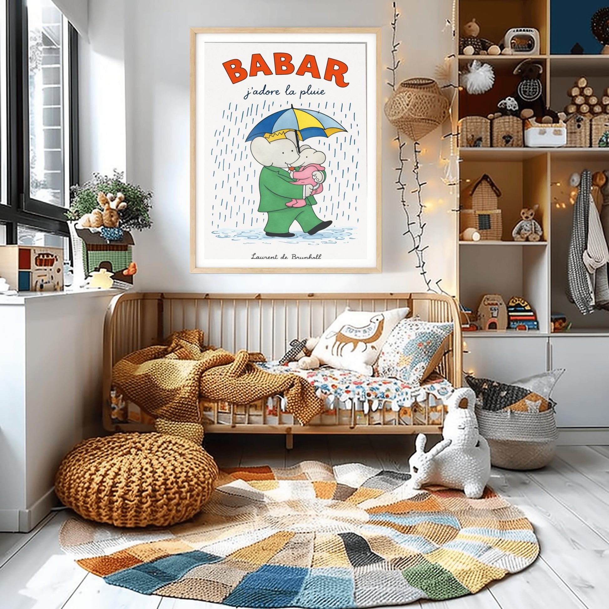 A vertical children's illustration poster titled "BABAR: j'adore la pluie" in orange and blue. King Babar, in a green suit and crown, is walking through the rain while holding a blue and yellow striped umbrella. He is carrying a small elephant wearing a pink rainsuit. They are walking through light blue puddles on a white background. The name "Laurent de Brunhoff" is at the bottom.