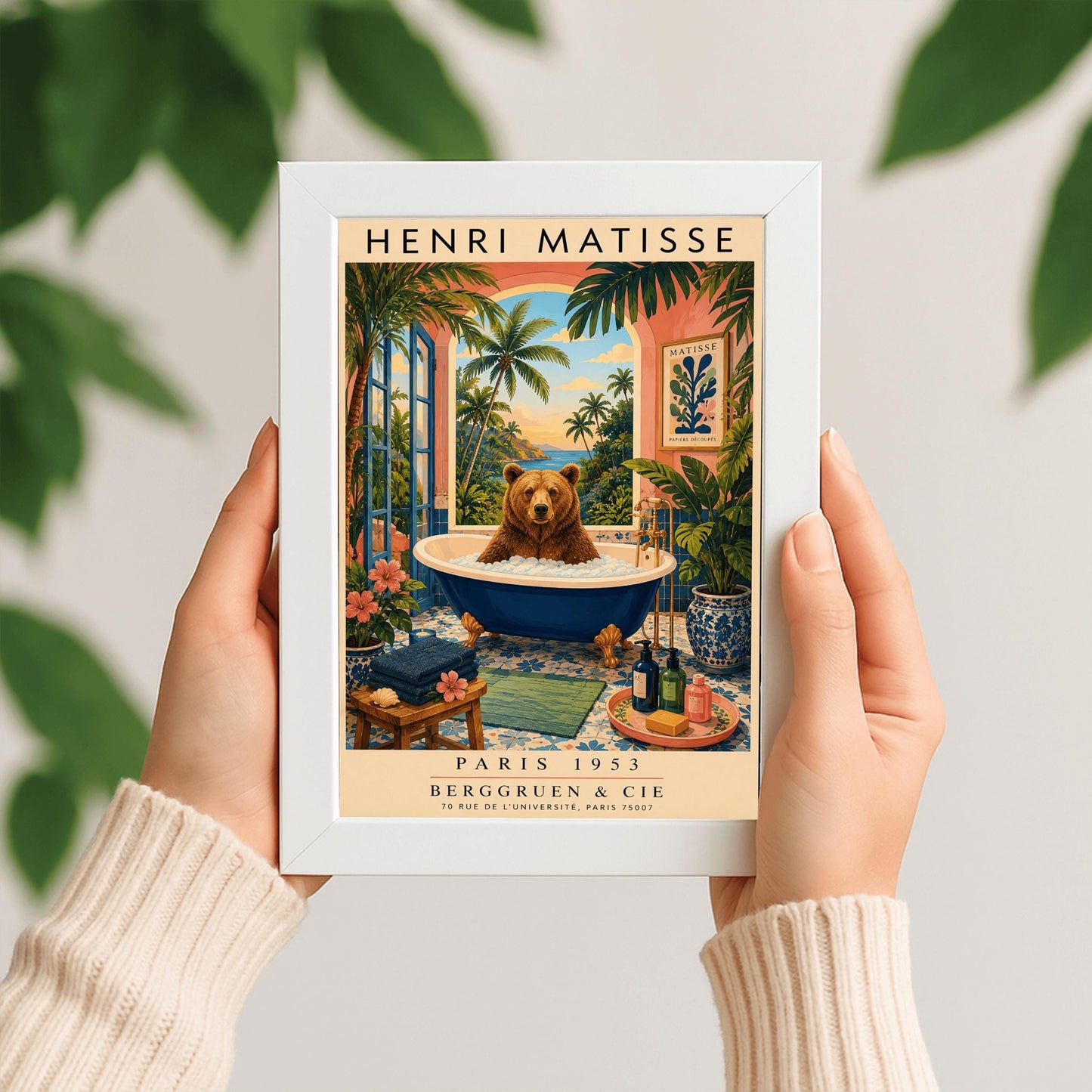 A vertical retro Henri Matisse exhibition poster on a wide cream border. The main image shows a surreal illustration of a large brown bear taking a bubble bath in a navy blue clawfoot tub with gold feet. The bathroom features blue patterned floor tiles, a pink wall with a framed Matisse cut-out poster, and a massive open arch window overlooking a tropical beach with palm trees and a blue ocean at sunset