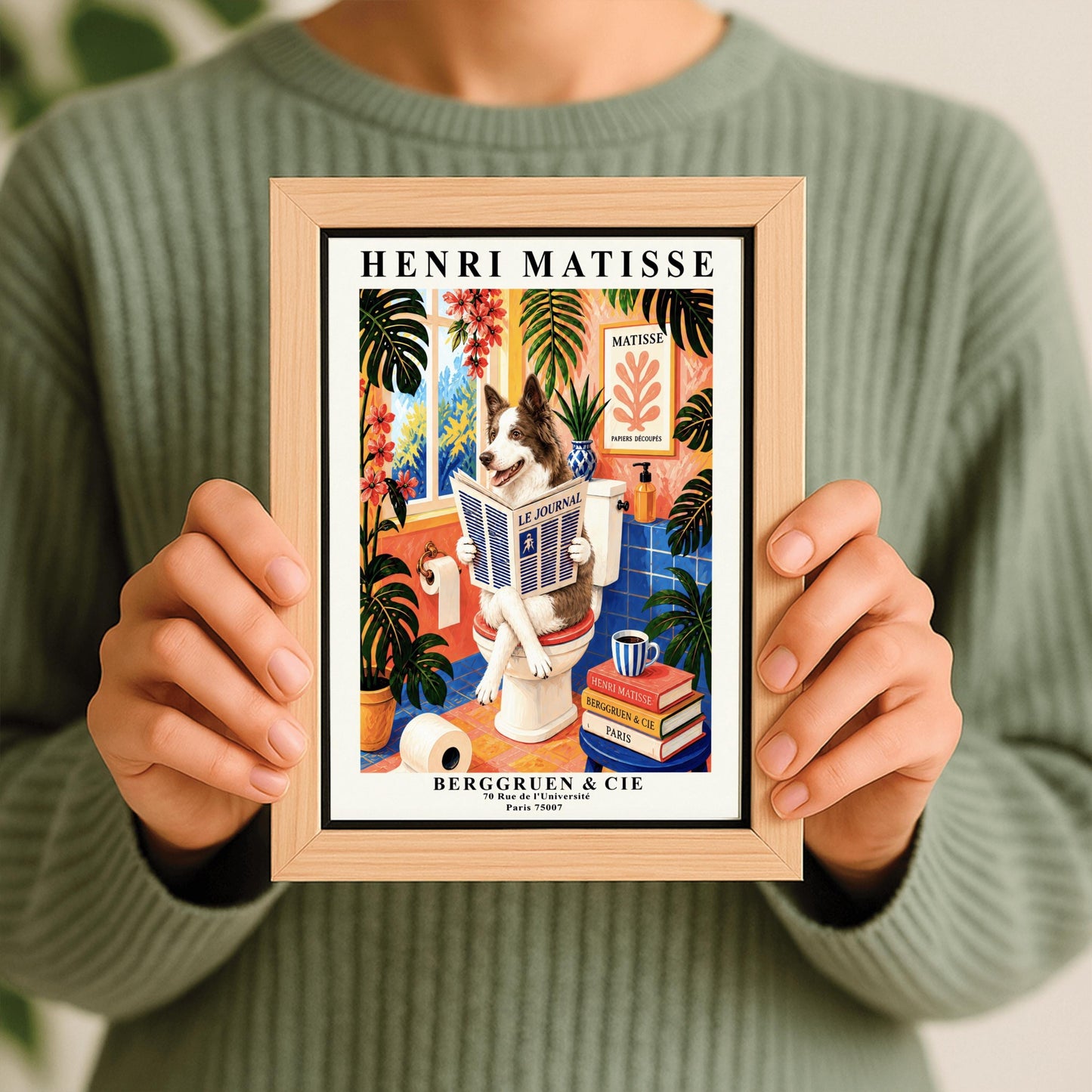 A vertical retro French exhibition poster styled after Henri Matisse with a wide ivory border. The central image shows a vibrant bathroom illustration where a fluffy brown-and-white border collie dog sits upright on a white toilet, holding and reading a newspaper titled "LE JOURNAL" with a happy, alert expression. The room features cobalt blue floor and wall tiles, coral pink walls, and large potted monstera plants with cascading pink flowers