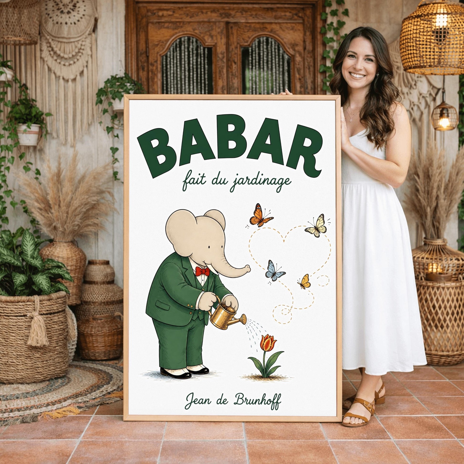 A vertical fine art exhibition poster featuring a classic illustration of Babar the Elephant by Jean de Brunhoff. Set within a wide white border on a textured off-white background, the elephant is shown in a green suit and red bowtie watering a red tulip with a gold can. Four butterflies fly nearby, leaving a dotted line that forms a heart shape. Bold green text at the top reads "BABAR fait du jardinage".