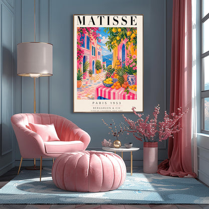 A vertical maximalist art print styled as a Henri Matisse exhibition poster. The scene depicts a vibrant, colorful street in a Mediterranean coastal town. In the foreground, a table with a pink and white striped cloth is piled high with lemons, oranges, and a pineapple. Hot pink and yellow buildings with blue shutters line a cobblestone path that leads toward a blue sea under a bright sky. Lush green trees with yellow lemons and pink flowers frame the view.