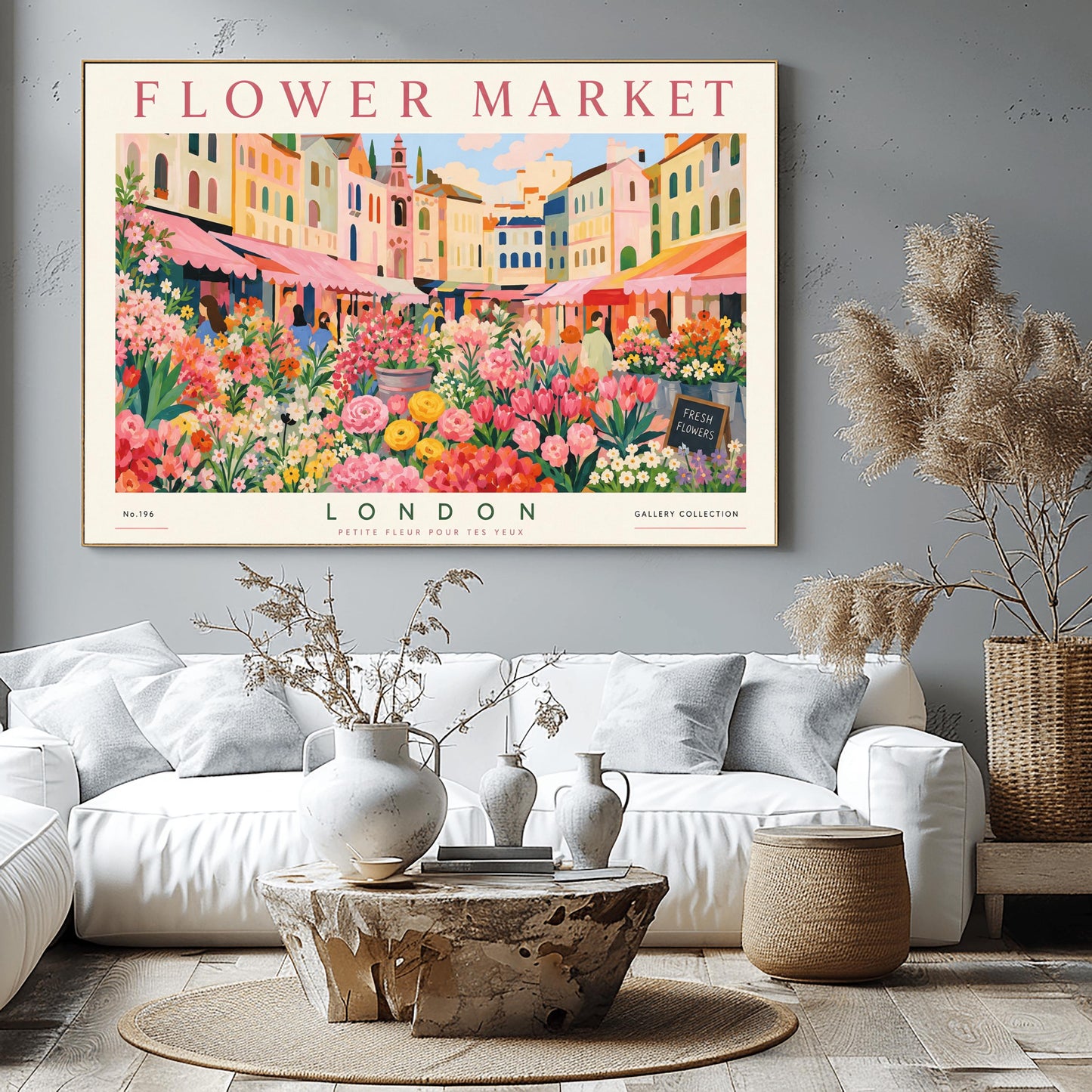 A vintage-style exhibition poster titled "FLOWER MARKET" at the top and "LONDON" at the bottom. The illustration depicts a vibrant open-air market scene packed with dense stalls of pink tulips, yellow ranunculus, and assorted green foliage. In the background, a row of colorful, multi-story pastel buildings stands under a light blue sky with soft white clouds, with shoppers walking between the stalls.