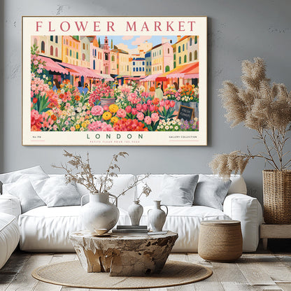 A vintage-style exhibition poster titled "FLOWER MARKET" at the top and "LONDON" at the bottom. The illustration depicts a vibrant open-air market scene packed with dense stalls of pink tulips, yellow ranunculus, and assorted green foliage. In the background, a row of colorful, multi-story pastel buildings stands under a light blue sky with soft white clouds, with shoppers walking between the stalls.