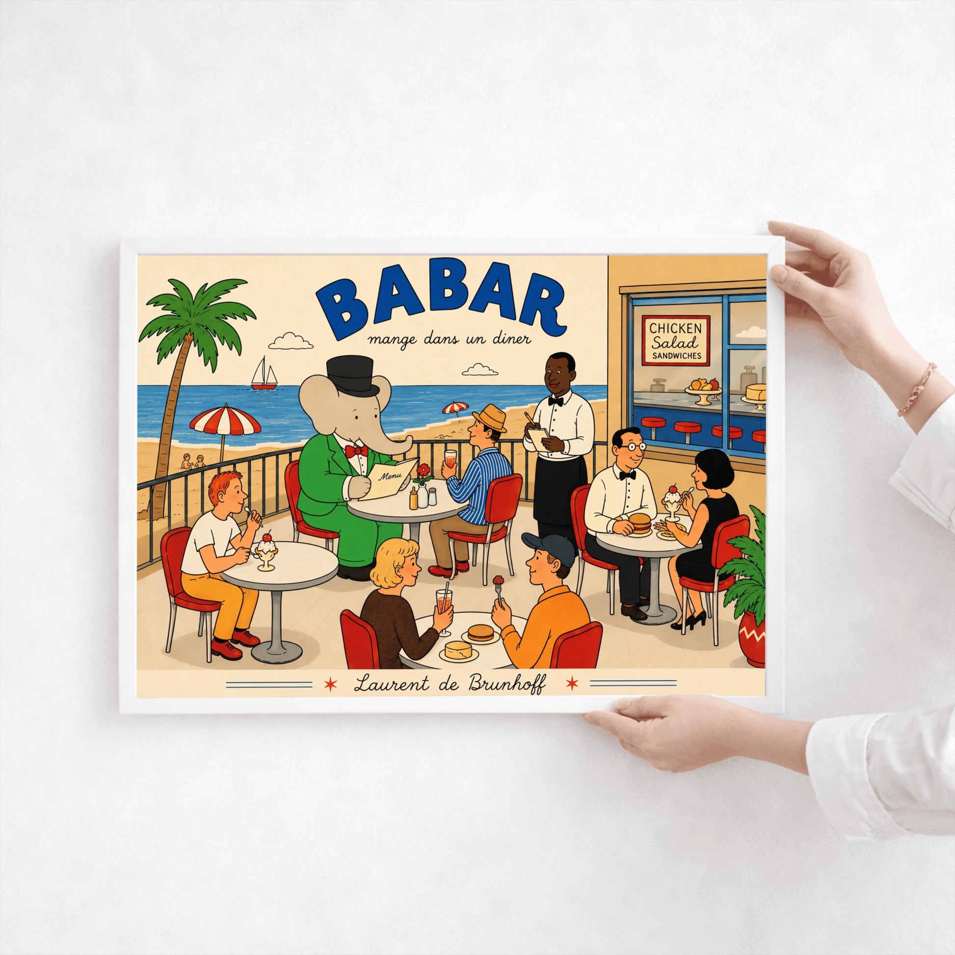 A bright 1950s-style illustration poster titled "BABAR mange dans un diner" in bold blue and black script. The scene shows an outdoor diner balcony overlooking a sandy beach and blue ocean with a sailboat. On the left, the cartoon elephant King Babar sits at a round white table in a green suit and top hat, reading a menu. Several other patrons are seated at tables on red chairs eating burgers and ice cream sundaes, while a waiter in a bowtie takes notes.