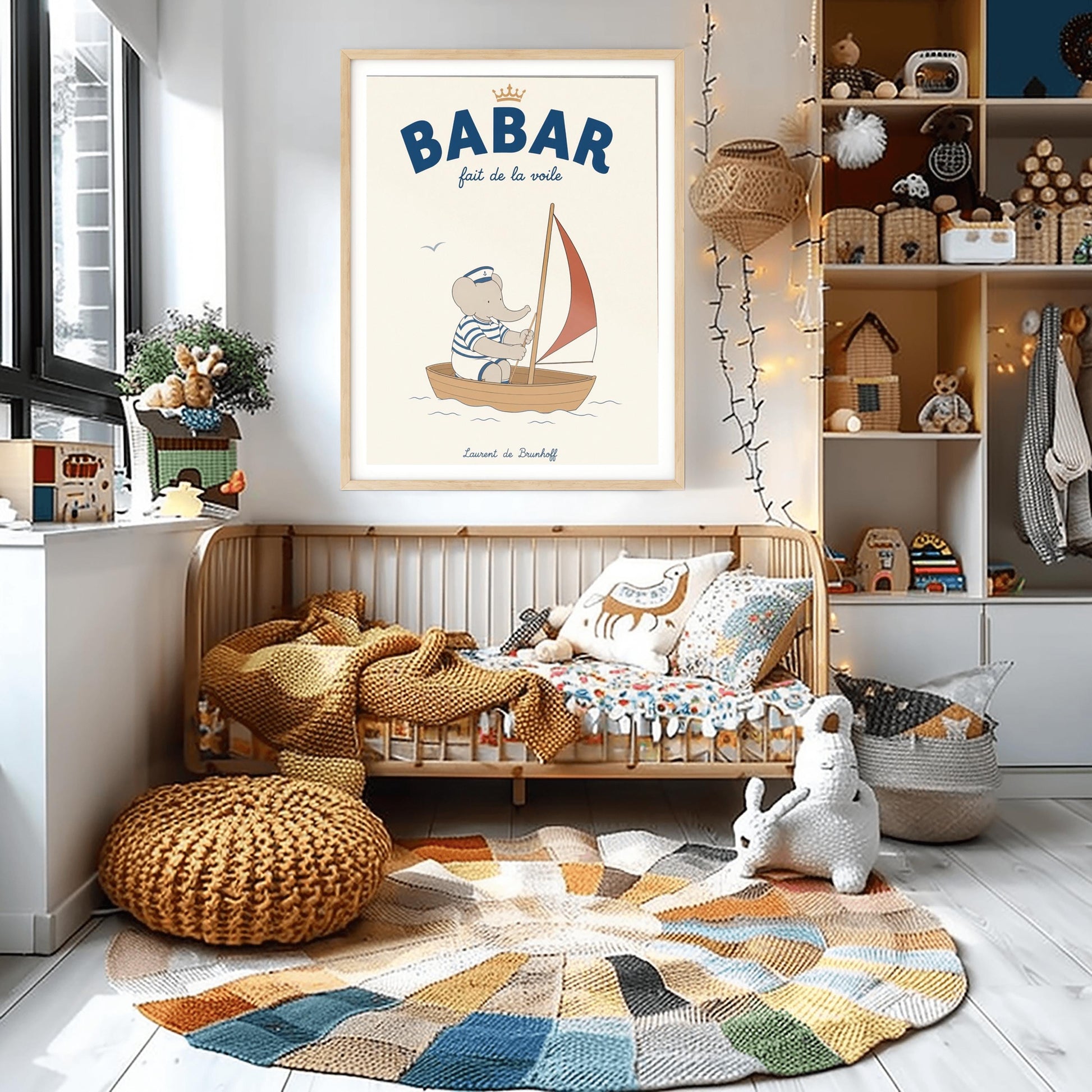A vertical storybook-style art print featuring Babar the Elephant sailing a small boat. Babar wears a blue and white striped shirt and a white sailor's hat with an anchor. He is sitting in a brown wooden boat with a red and white sail. A single seagull flies in the creamy off-white sky. The top reads "BABAR fait de la voile" with a small gold crown.