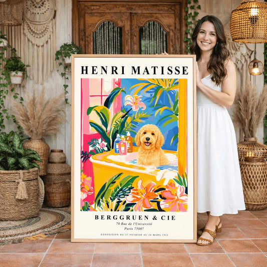 A vertical minimalist fine art exhibition poster in the style of Henri Matisse, shown framed on a wall above a luxury white bathtub. The poster has a wide white border with bold black text reading "HENRI MATISSE" and "BERGGRUEN & CIE". In the center painting, a fluffy golden doodle dog sits happily inside a yellow bathtub surrounded by vibrant pink, blue, and green tropical plants and orange flowers.