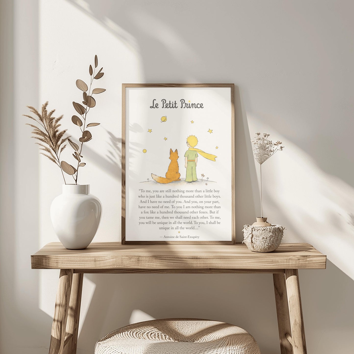 A vertical art print featuring a minimalist illustration of the Little Prince and the Fox from behind. The Prince wears a green suit and a long, flowing yellow scarf, standing next to an orange fox on a small grey mound. Above them are several simple yellow stars and a ringed planet. Below the illustration is a famous quote about "taming" and uniqueness from the book, attributed to Antoine de Saint-Exupéry.