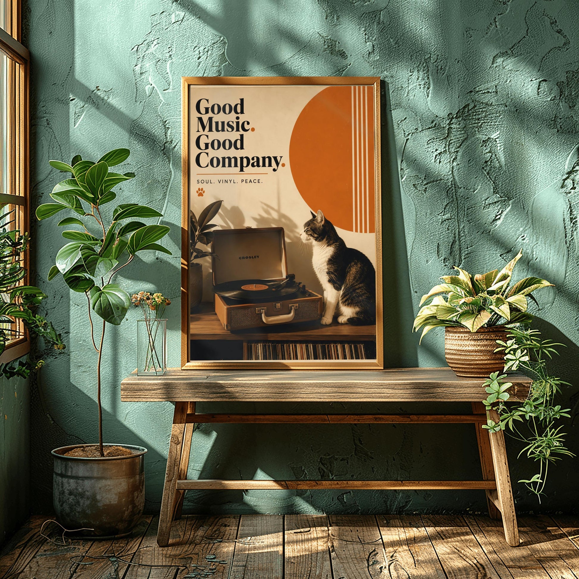 A vertical retro fine art poster titled "Good Music. Good Company." on a wide cream border. The design features a bold black serif heading on the left above the text "SOUL. VINYL. PEACE." and a small orange paw print. In the central artwork, a black and white tuxedo cat sits contentedly next to an open tan Crosley record player spinning a vinyl record. A large orange sun shape with white vertical stripes and a potted rubber plant decorate the background.