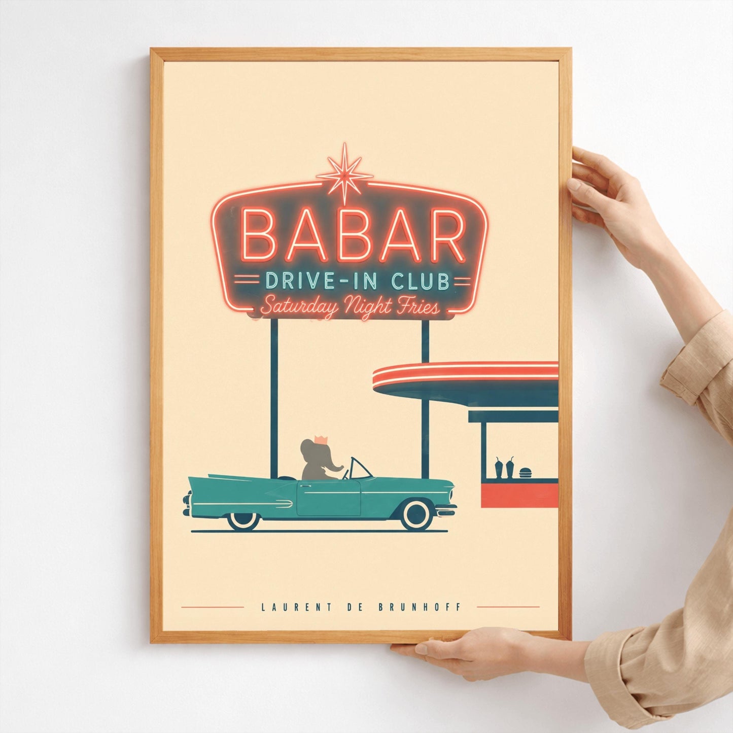 A minimalist graphic vintage-style poster on a solid cream background. At the top, a large retro neon-style sign glows with a red border and teal lettering that reads "BABAR DRIVE-IN CLUB - Saturday Night Fries". Below the sign, a silhouette of a cartoon elephant wearing a crown sits inside a classic teal 1950s convertible car. The car is parked next to a simplified red and teal drive-in order window featuring two milkshakes and a burger silhouette.
