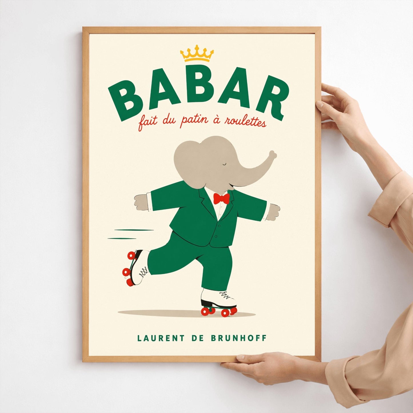 A vertical storybook-style art print of Babar the Elephant roller skating against a cream background. Babar is wearing his signature green suit and red bow tie. He is balanced on white roller skates with red wheels, with one foot lifted behind him. The top of the print features the word "BABAR" in large green letters above the red script text "fait du patin à roulettes" and a small gold crown. The name "LAURENT DE BRUNHOFF" is printed at the bottom.